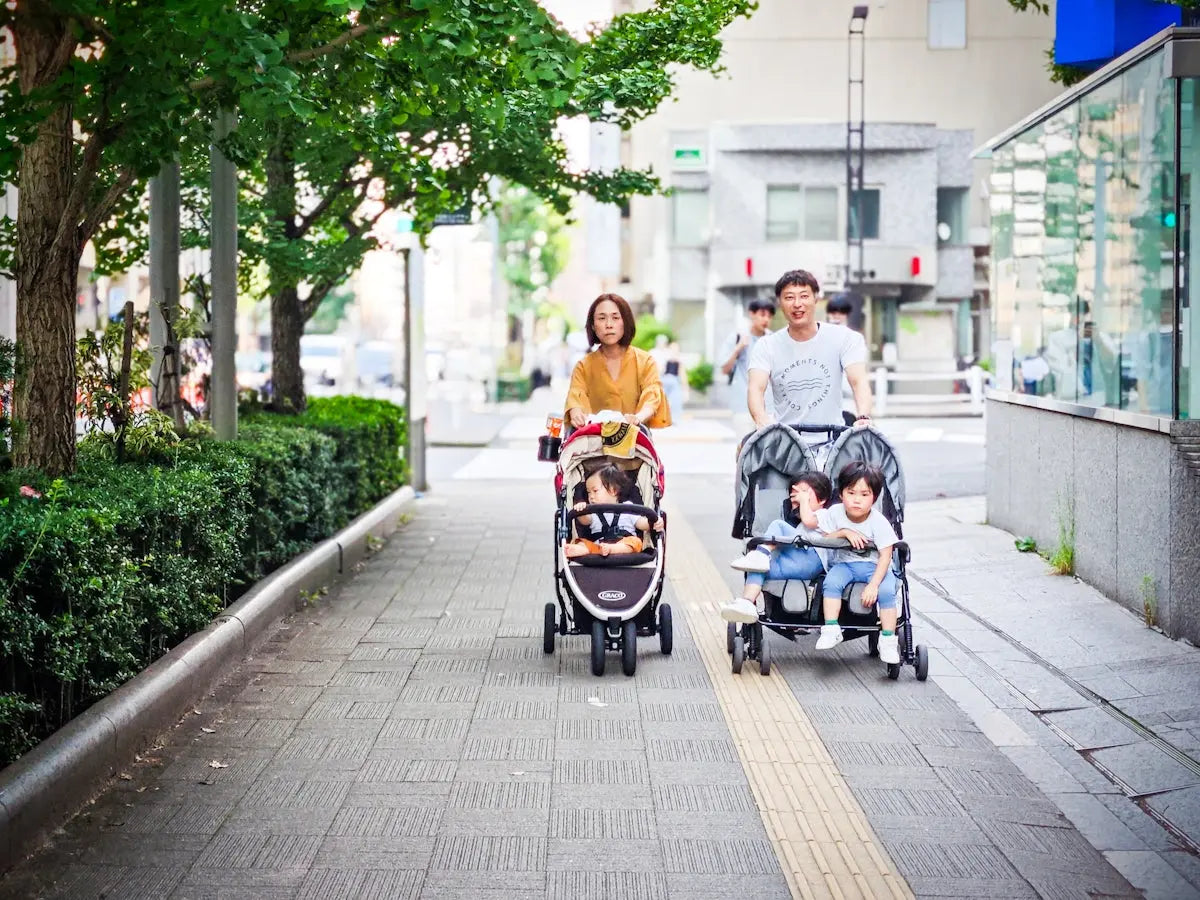 Parents pushing children in strollers on sidewalk.