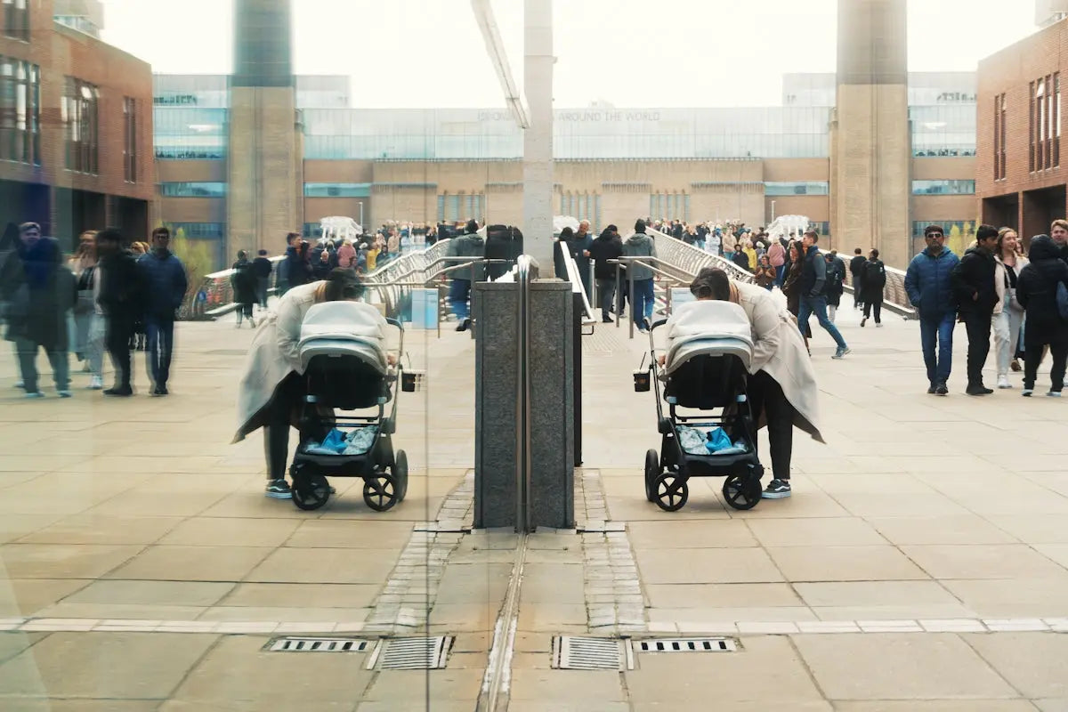 People and strollers reflected in a modern building facade