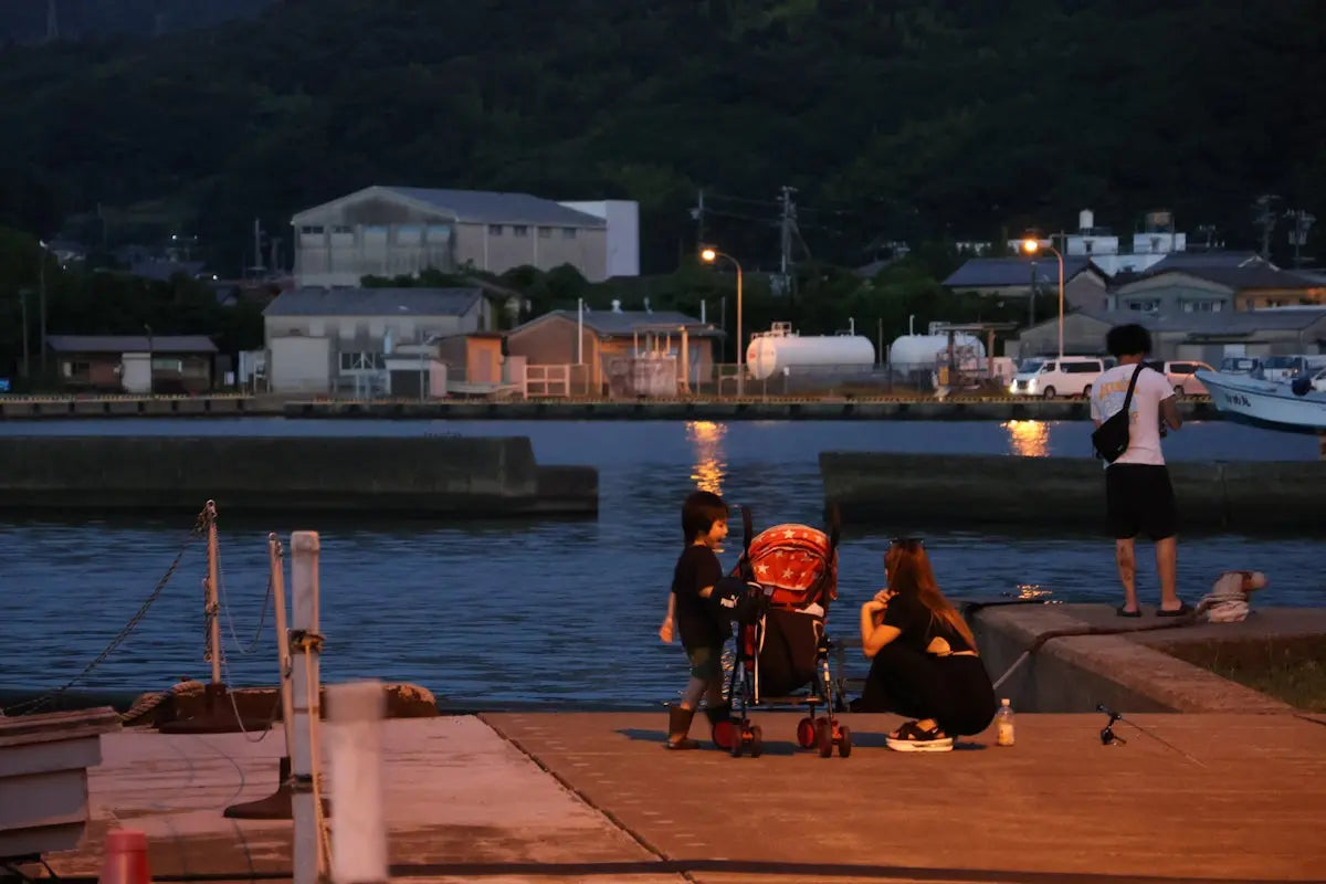People fishing by the water at dusk.