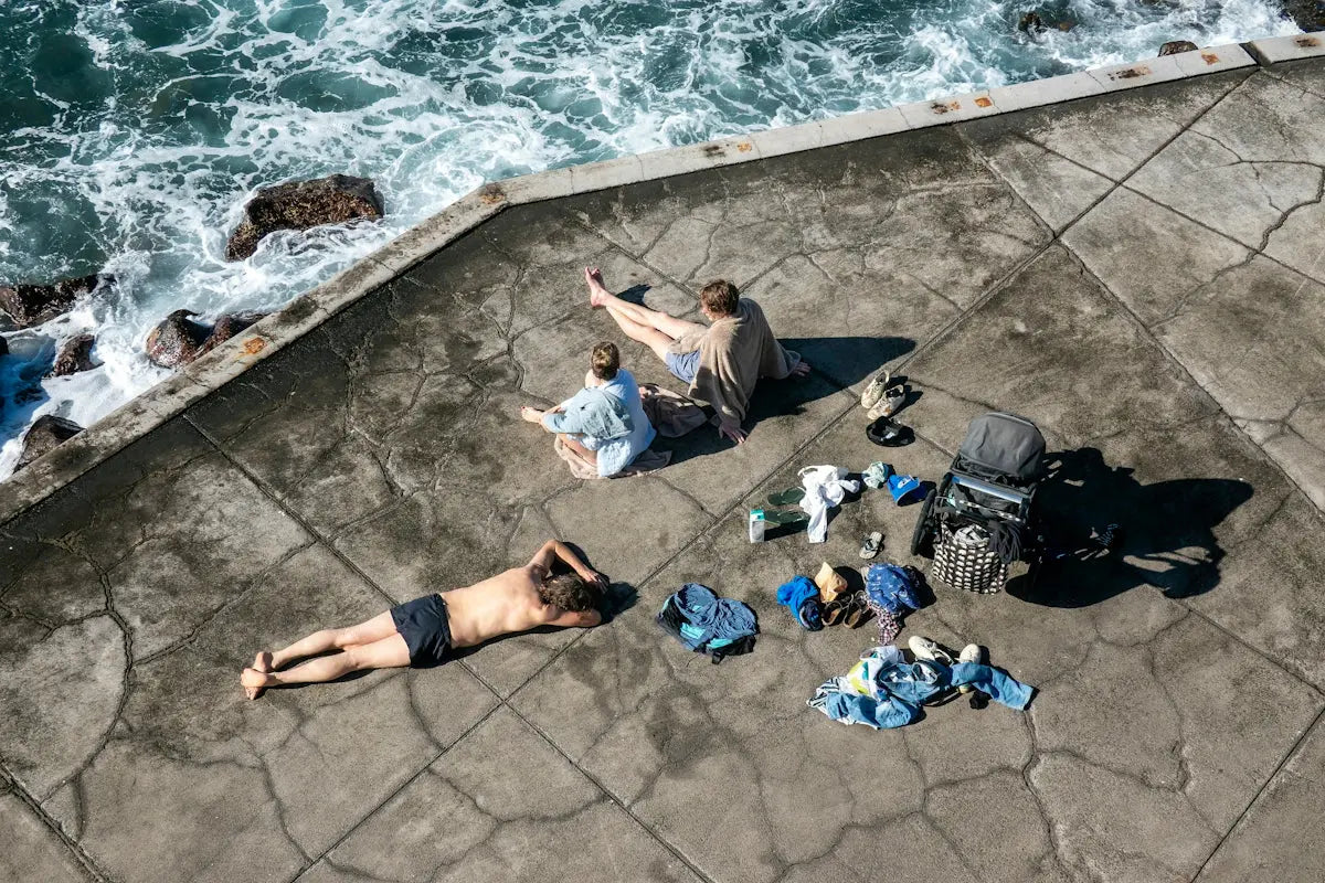 People relaxing on a concrete surface by the ocean.