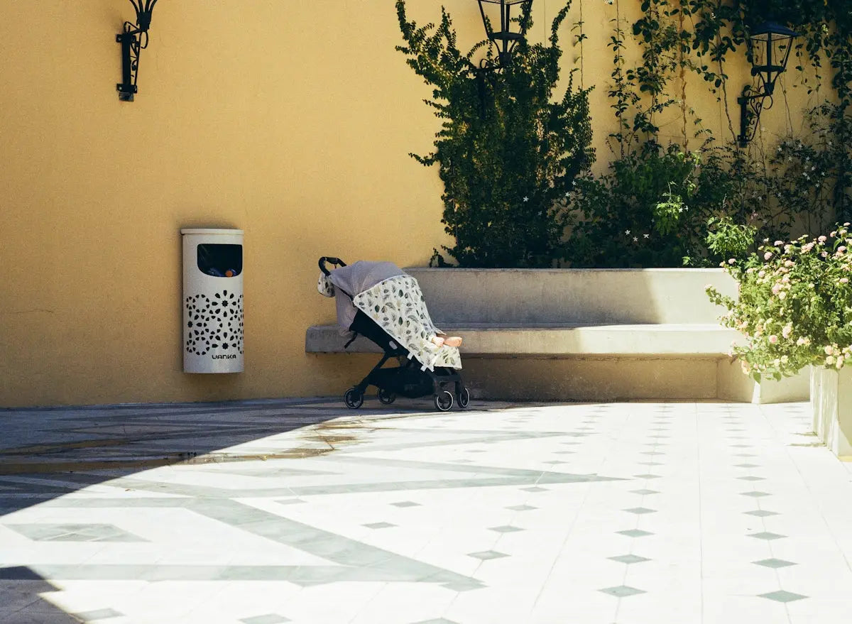 A stroller sits on a patterned patio near a bench.
